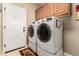 Well-equipped laundry room with front-loading washer and dryer and overhead cabinets at 23791 W Magnolia Dr, Buckeye, AZ 85326