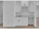 Stylish wet bar with white cabinetry, marble countertops, and a built-in wine rack, perfect for entertaining at 28834 N 175Th Ave, Surprise, AZ 85387