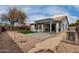 Desert backyard with a covered patio, mature tree, brick border, artificial grass, and rock landscape at 3423 E Crescent Way, Gilbert, AZ 85298