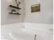 Bright white bathroom features shelving with a tub beneath along with neutral colored modern artwork at 4237 E Sierra Madre Ave, Gilbert, AZ 85296