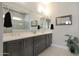 This modern bathroom features dual sinks, dark-stained cabinetry and a sleek walk-in shower at 5195 N 207Th Dr, Buckeye, AZ 85396