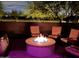 A nighttime view showcases a patio area with a lit fire pit surrounded by comfortable seating with trees in the backdrop at 5195 N 207Th Dr, Buckeye, AZ 85396