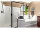Bright bathroom featuring dual sinks, a soaking tub, and a seamless glass shower at 520 S 196Th Dr, Buckeye, AZ 85326