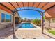 Pool area featuring shade structure, lounge chairs, blue pool, green grass, desert landscaping, fence at 520 S 196Th Dr, Buckeye, AZ 85326