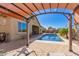 Backyard pool area with cozy seating, shade covering, landscaping, fence, and blue skies at 520 S 196Th Dr, Buckeye, AZ 85326