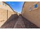 Paver walkway with gravel landscaping leading to wooden gate between beige stucco walls at 520 S 196Th Dr, Buckeye, AZ 85326