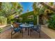 Outdoor patio area with ivy-covered building and stone table with 4 chairs at 6701 N Scottsdale Rd # 15, Scottsdale, AZ 85250