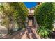 Pathway through a lush courtyard covered in flowering vines and plants leading to an iron gate and entrance at 6701 N Scottsdale Rd # 15, Scottsdale, AZ 85250
