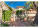 The courtyard entrance is framed by a beautiful brick wall, lush green foliage, and a secure wrought iron gate at 6701 N Scottsdale Rd # 15, Scottsdale, AZ 85250