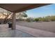 Covered back patio leads to a xeriscaped yard with mature trees and desert landscaping at 10468 E Raintree Dr, Scottsdale, AZ 85255