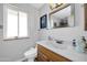 Well-lit bathroom featuring a bright window, vanity with framed mirror, and neutral wall color at 10842 W Sarabande Cir, Sun City, AZ 85351