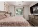 Comfortable bedroom featuring a plush bed, natural light, and a dresser with a wall-mounted TV at 12887 N 93Rd Dr, Peoria, AZ 85381