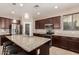 Bright kitchen featuring granite countertops, stainless steel appliances, dark wood cabinetry and an island with seating at 12887 N 93Rd Dr, Peoria, AZ 85381