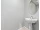 Bright bathroom featuring a pedestal sink with a round mirror and a white textured wall at 14808 E Miramonte Way, Fountain Hills, AZ 85268