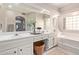 Bathroom with double sinks, a large mirror, and soaking tub at 15481 W Amelia Dr, Goodyear, AZ 85395