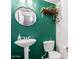 Stylish half bathroom with green accent wall, a pedestal sink, and unique decorations at 16825 N 14Th St # 125, Phoenix, AZ 85022