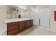 Bathroom boasts a double sink vanity with wood cabinets, tiled floor, and glass enclosed shower at 16927 W Desert Blossom Way, Surprise, AZ 85387