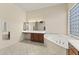 Bright bathroom boasts a double sink vanity, soaking tub, and glass block window for natural light at 16927 W Desert Blossom Way, Surprise, AZ 85387