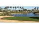 Scenic golf course view with green grass, sand traps, a pond surrounded by rock, and palm trees under a blue sky at 16927 W Desert Blossom Way, Surprise, AZ 85387