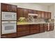 Gourmet kitchen showcases dark wood cabinetry, tile backsplash, and modern appliances at 16927 W Desert Blossom Way, Surprise, AZ 85387