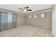 Bright bedroom with a ceiling fan, large window with curtains, and neutral-toned carpet at 1922 E Saltsage Dr, Phoenix, AZ 85048