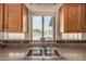 Close-up of a stainless steel kitchen sink with tiled backsplash and view from the window at 2535 N Pinnule Cir, Mesa, AZ 85215