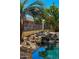 Lush backyard pool area with a rock waterfall feature, offering a serene and tropical oasis for relaxation and recreation at 2535 N Pinnule Cir, Mesa, AZ 85215