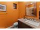 Bathroom featuring orange walls, a vanity with sink, mosaic tile accents, and a framed mirror at 30556 N Sage Dr, Peoria, AZ 85383