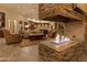 A cozy living room featuring a stone fireplace, comfortable seating, and an open floor plan leading into the kitchen at 30556 N Sage Dr, Peoria, AZ 85383