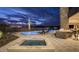 An outdoor area featuring a pool, hot tub, lounge chairs, outdoor cooking area and desert landscaping at twilight at 30556 N Sage Dr, Peoria, AZ 85383