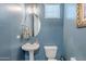 Charming powder room with blue walls, a pedestal sink, and a decorative mirror, creating an inviting space at 3432 E Jasper Dr, Gilbert, AZ 85296