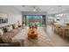 Open-concept living room with sliding glass doors and bright, neutral decor leads to the kitchen at 41285 W Sussex Dr, Maricopa, AZ 85138