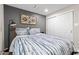 Cozy bedroom features a comfortable bed with striped bedding, a modern lamp and a closet at 13614 N 38Th Pl, Phoenix, AZ 85032