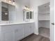Bright main bathroom with double sinks, white cabinets, modern lighting, and a walk-in closet at 19008 N Lousandra Dr, Maricopa, AZ 85138