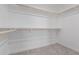 A walk-in closet with wooden bars, shelves, and neutral carpet, providing ample storage space at 19008 N Lousandra Dr, Maricopa, AZ 85138