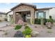 Charming home featuring a stone-accented porch, desert landscaping with lush green shrubs, and cacti at 20528 W Coolidge St, Buckeye, AZ 85396