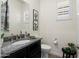 Elegant powder room featuring granite countertops, black cabinetry, and framed cactus wall art at 20528 W Coolidge St, Buckeye, AZ 85396
