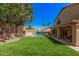 Serene backyard with artificial turf, mature trees, and a gated pool for Gathering enjoyment and privacy at 2108 E Tecoma Rd, Phoenix, AZ 85048
