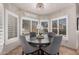 Bright dining area with a chandelier, modern gray chairs, and views of the pool through large windows at 2108 E Tecoma Rd, Phoenix, AZ 85048