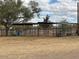 A view of horse stalls in a sandy horse property with mature trees and a partially cloudy sky at 2151 S Calle Del Marcos --, Casa Grande, AZ 85194