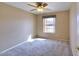 A cozy bedroom with neutral carpet and walls, a ceiling fan, and a bright window with a view to the outside at 604 W Villa Rita Dr, Phoenix, AZ 85023