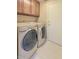 Convenient laundry room featuring washer, dryer, overhead cabinets, and white tile flooring at 604 W Villa Rita Dr, Phoenix, AZ 85023