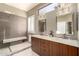 Bright bathroom with double vanity, quartz countertop, wood cabinets, walk in shower and tiled floor at 6820 W Angela Dr, Glendale, AZ 85308