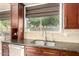 Close up of the kitchen sink, stainless steel appliances, granite countertops, and dark wood cabinets at 6820 W Angela Dr, Glendale, AZ 85308
