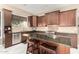 Close up of the kitchen with stainless steel appliances, dark wood cabinets, granite countertops, and tile backsplash at 6820 W Angela Dr, Glendale, AZ 85308