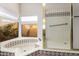 Bright bathroom with a tiled tub and glass enclosed shower at 7656 W Wagoner Rd, Glendale, AZ 85308