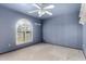 Bedroom with arched window, ceiling fan, and blue walls at 7656 W Wagoner Rd, Glendale, AZ 85308