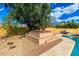Inviting backyard hot tub with stone surround and a large mature tree, perfect for relaxation and privacy at 7656 W Wagoner Rd, Glendale, AZ 85308