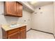 Functional laundry room with utility sink, storage cabinets, and vinyl flooring at 7656 W Wagoner Rd, Glendale, AZ 85308