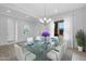 Formal dining room with glass table, white chairs, modern chandelier, and lots of natural light from the window at 8324 W Palo Verde Dr, Glendale, AZ 85305